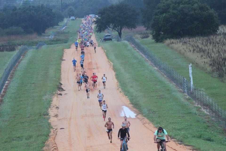 Runners and cyclists spread out along a rolling orange clay road on the Clermont Clay Trail loop in South Lake County, FL