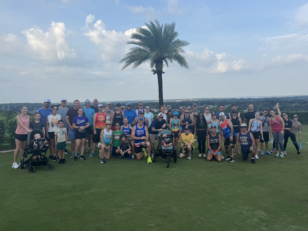 Large group of runners, walkers, and families with strollers on the lawn at The View at Clermont National in Clermont, FL after a Tuesday social run