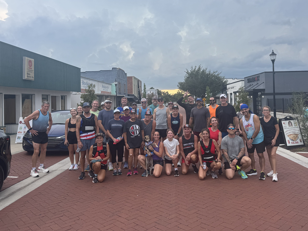 Runners gathered on a brick street in downtown Clermont, FL at dusk before a Dash Sports social run